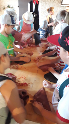 Die Grundschüler beim Anfertigen eines Lederbeutels